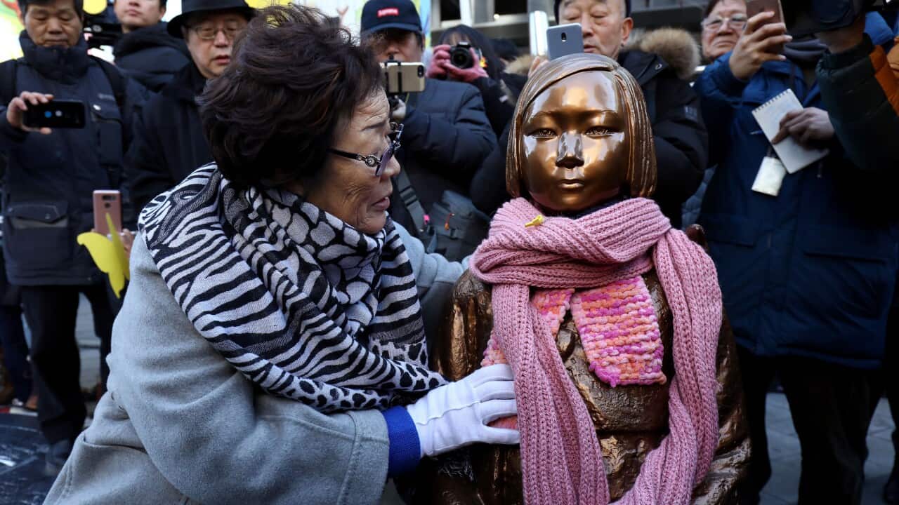 A woman sits next to a statue.