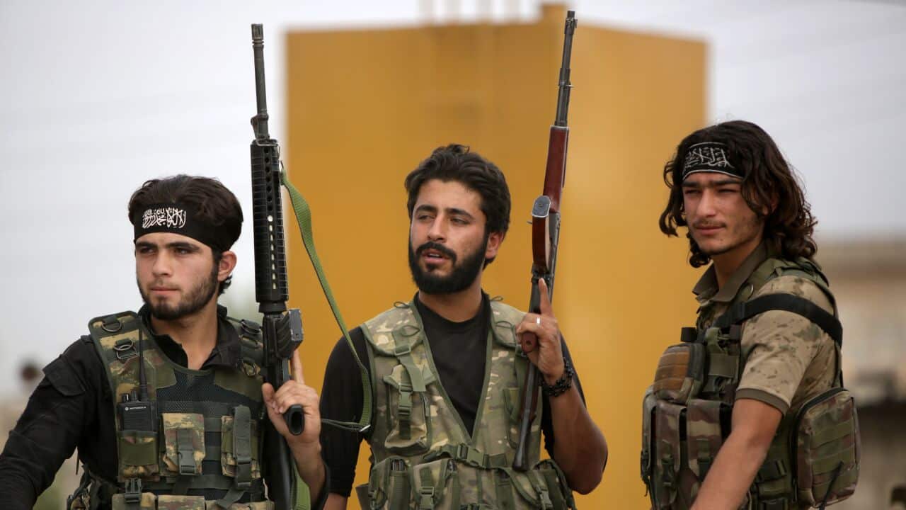 Turkey-backed Syrian fighters gather on the road between the Syrian towns of Tal Abyad and Kobane on the Turkish border.