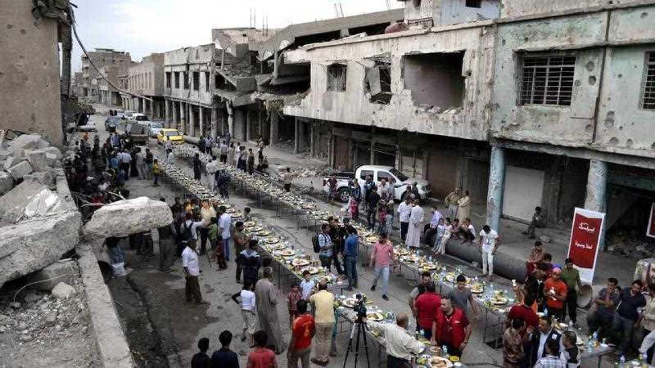 Mosul residents eat the Iftar meal to break their fasting amid the rubble of buildings in the old city of Mosul