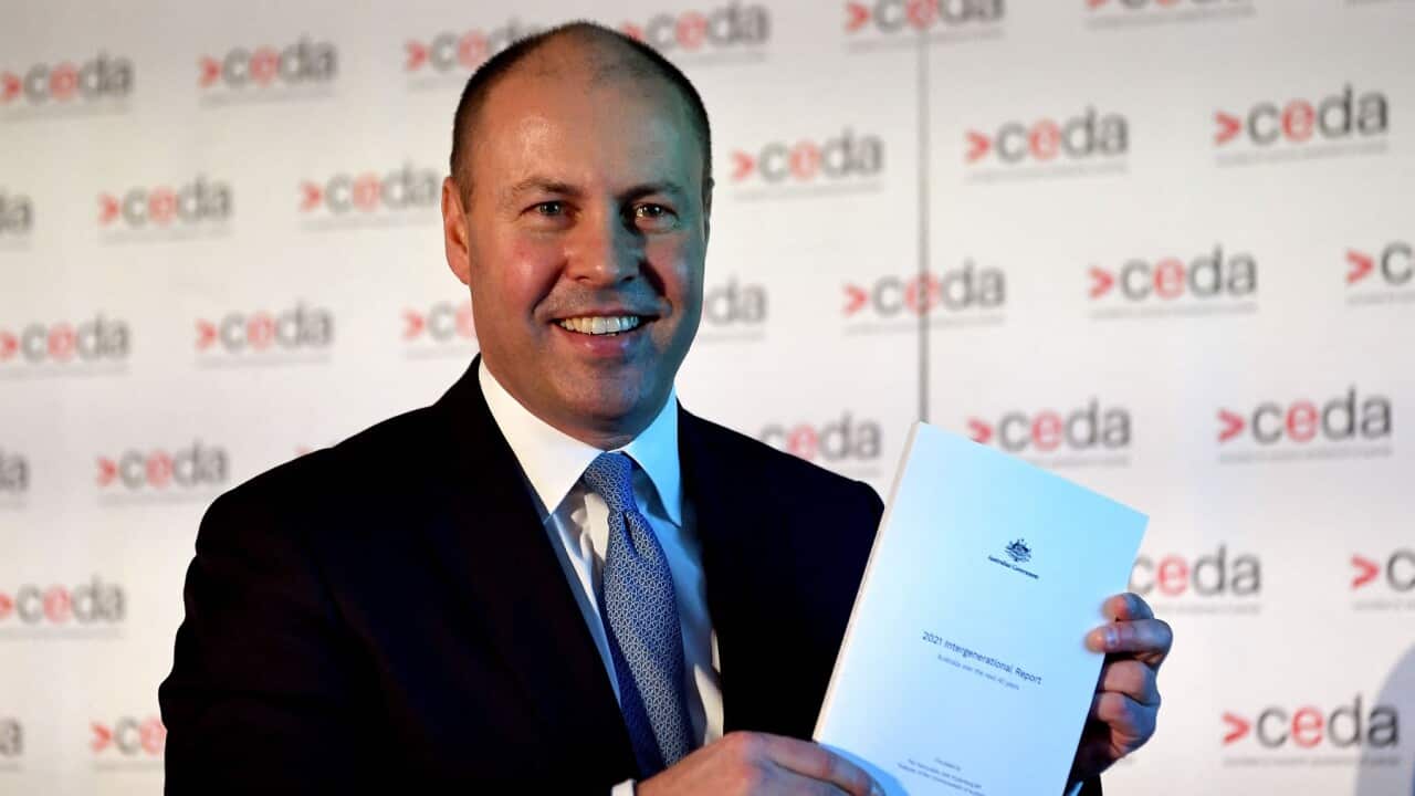 Treasurer Josh Frydenberg holds a copy of the 2021 Intergenerational Report