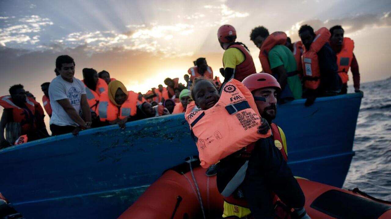 L'immagine del salvataggio di un piccolo migrante a bordo di un'imbarcazione nel Mediterraneo