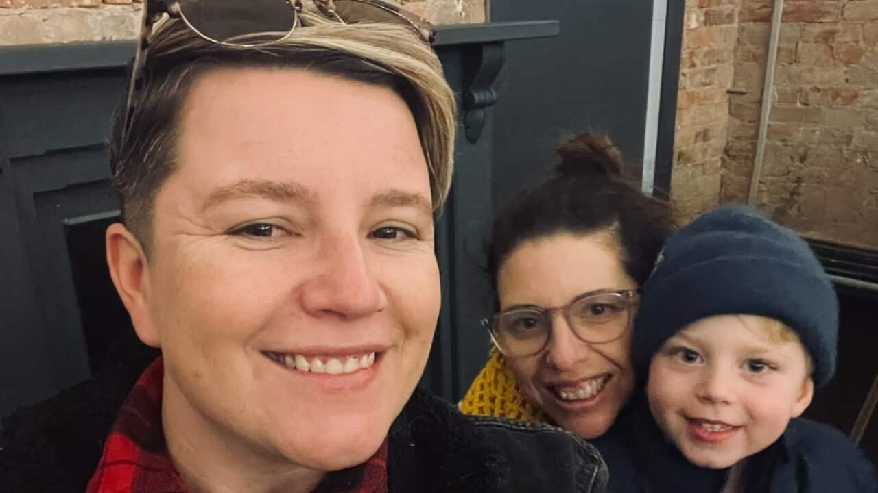 Two adults and a young boy smile for a photo.