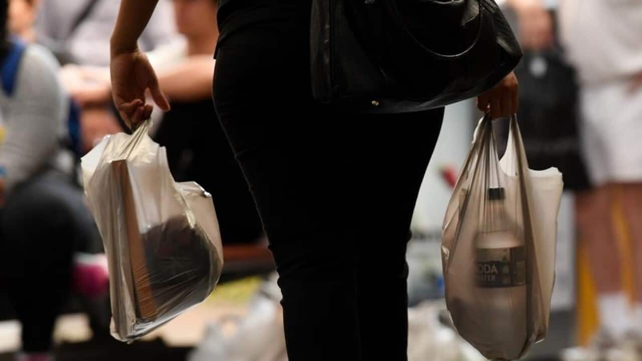 A customer holds plastic supermarket shopping bag