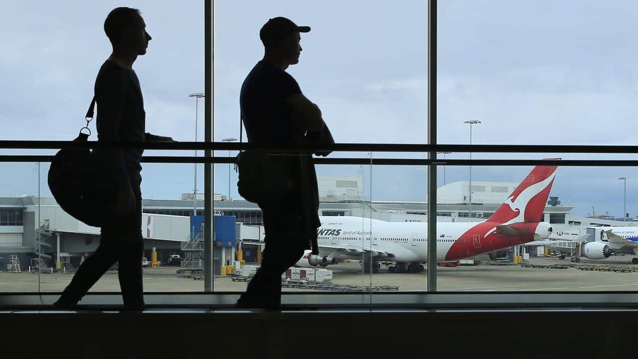 Two silhouetted people in front of a window at an airport.
