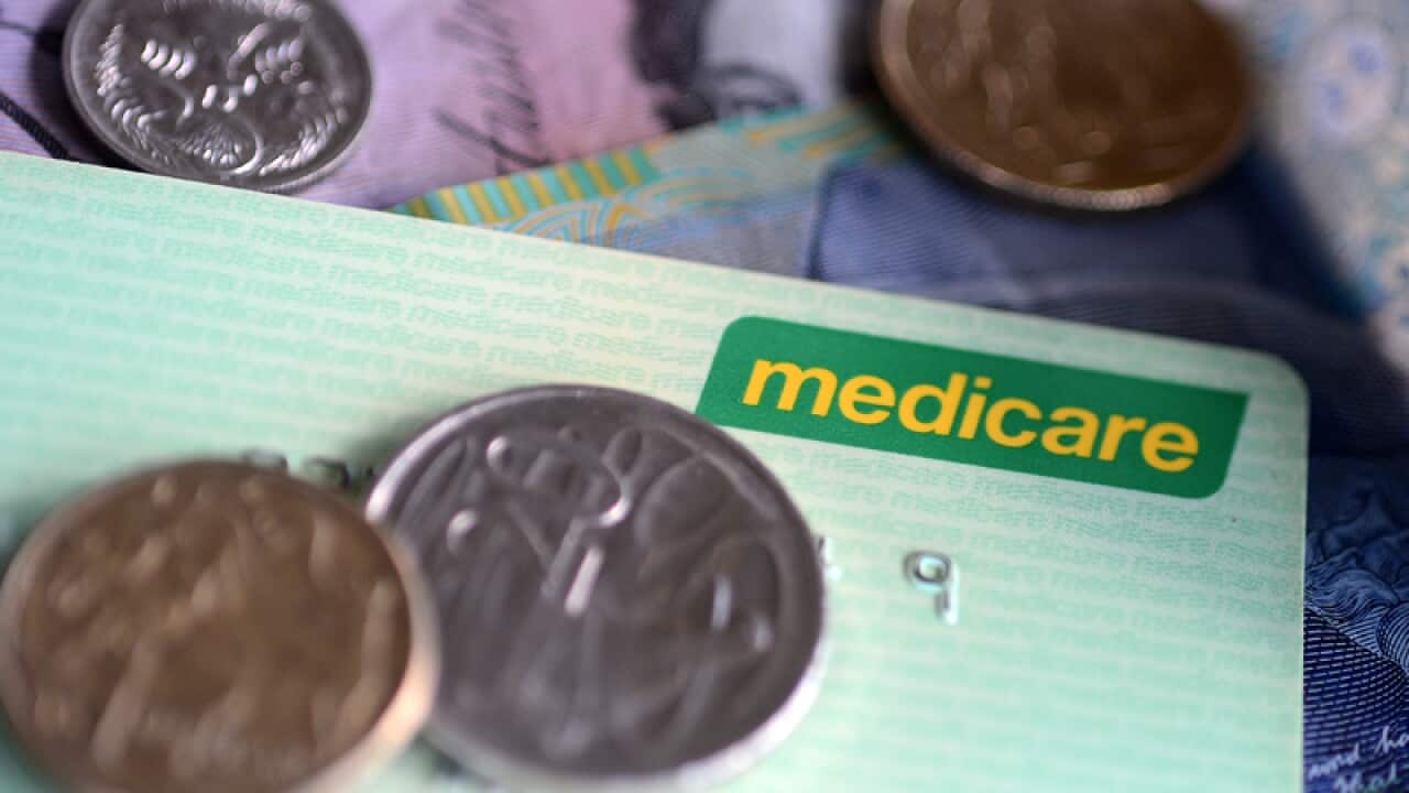 Bank notes and coins are seen with a Medicare Card in Brisbane