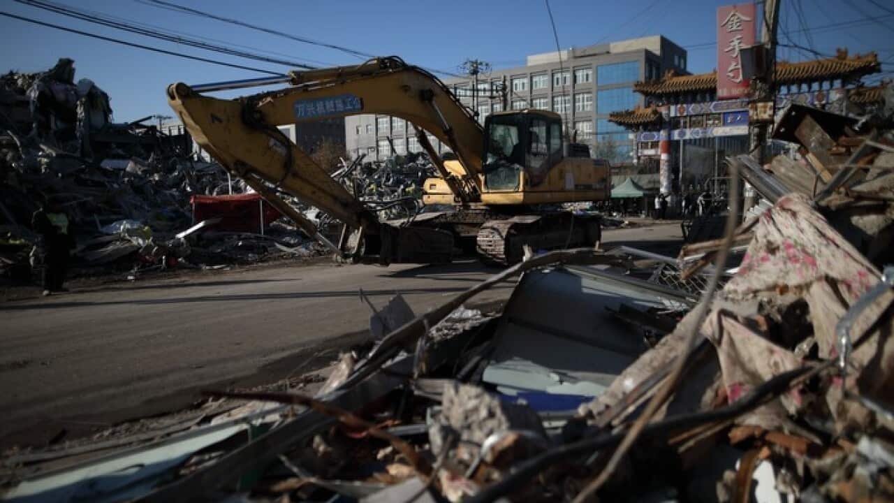 An excavator passes by apartment and factory debris after demolition in Xinjian village of Daxing district killing 19 people.