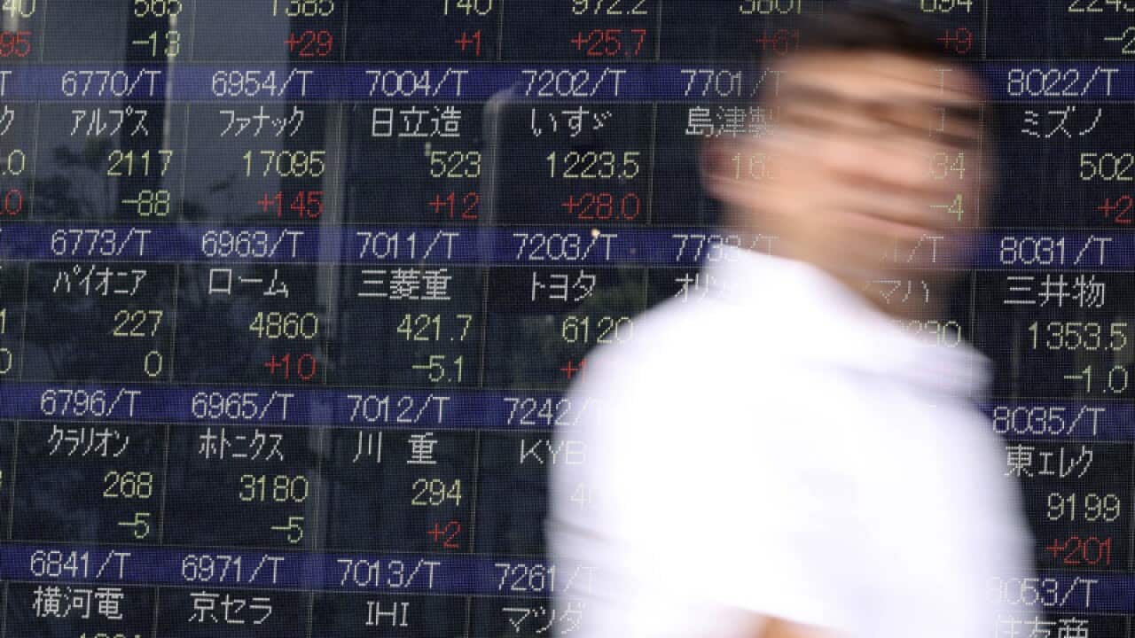 A man walks past an electronic stock board showing Japan's Nikkei 225