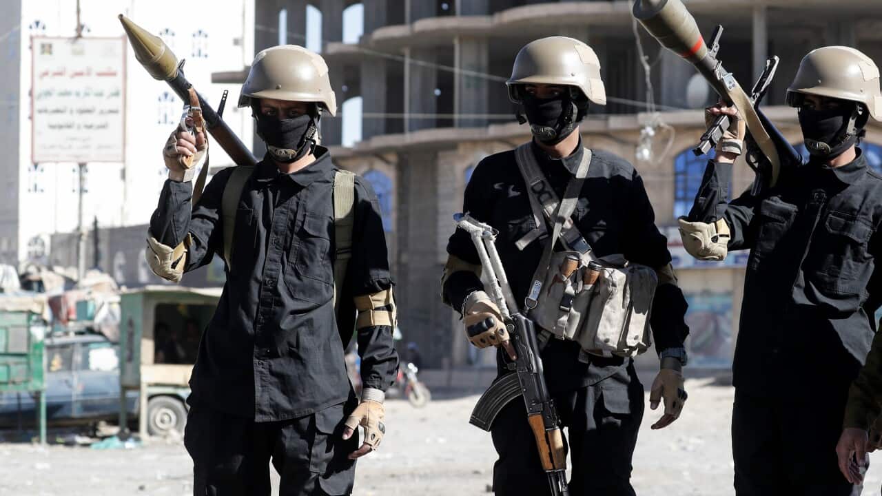 People wearing dark clothing, hard hats, and masks who are carrying weapons.