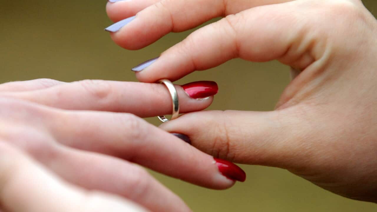 A same sex couple exchange rings.