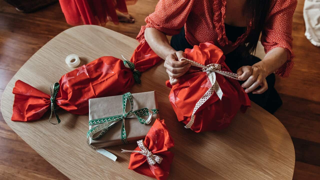 A woman wraps Christmas presents on a coffee table