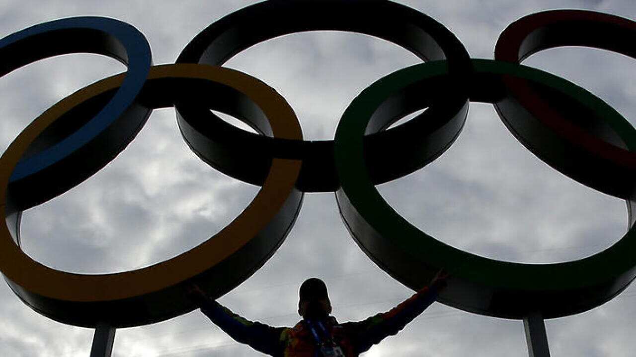 A volunteer poses with the Olympic Rings in Olympic Park as preparations continue for the 2014 Winter Olympics, Wednesday, Feb. 5, 2014, in Sochi, Russia. (AP Photo/Charlie Riedel)