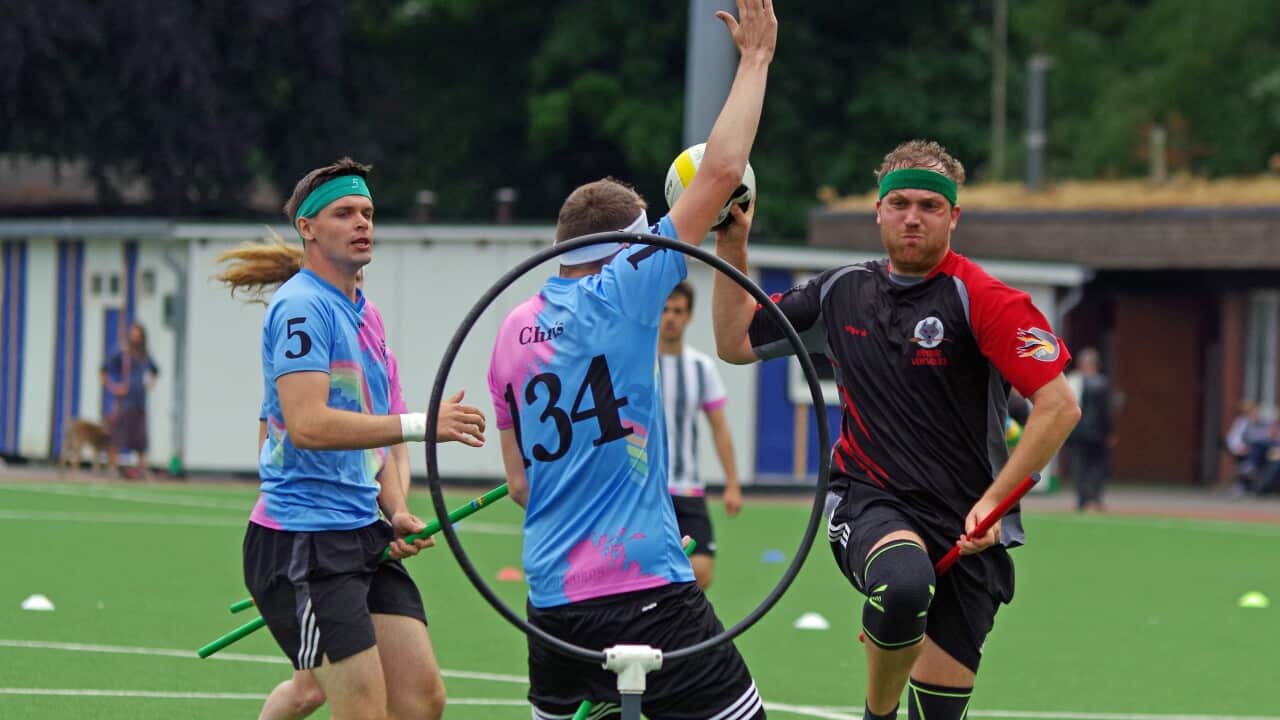 People in sport uniform are running. One is about to throw a ball into a ring.