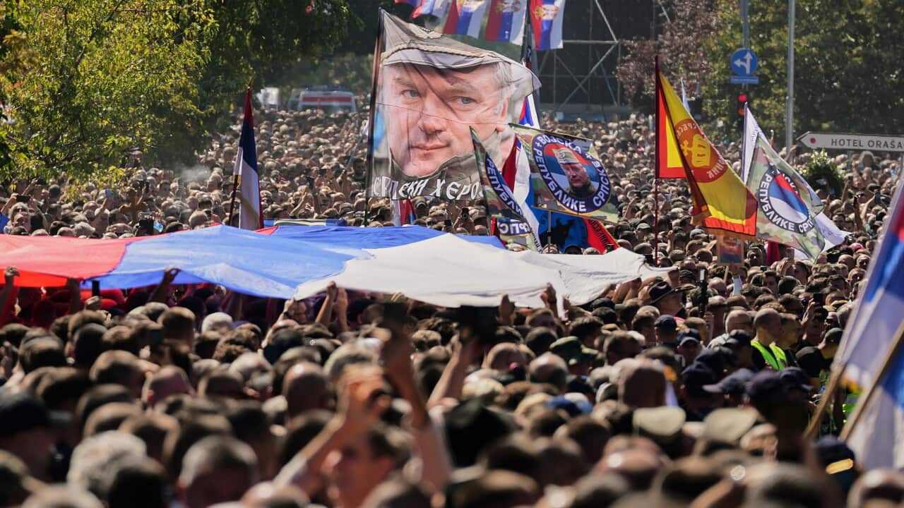People gathered for the funeral procession wave a flag showing the former Bosnian Serb army commander Ratko Mladic,