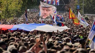 People gathered for the funeral procession wave a flag showing the former Bosnian Serb army commander Ratko Mladic,