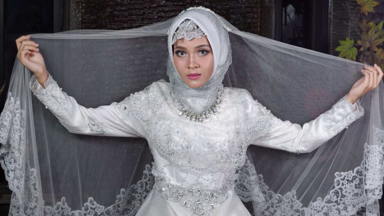 Portrait Of Bride Wearing Traditional Clothing Sitting Against Wall