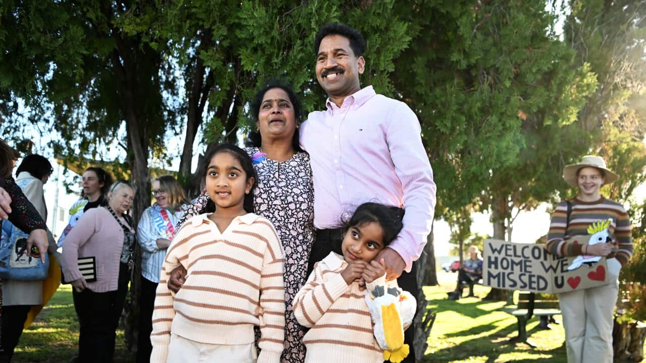 The Nadesalingam family standing in a park smiling
