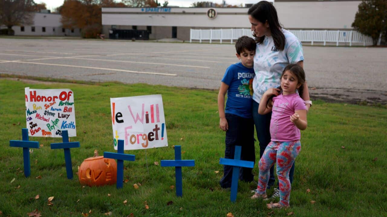 A woman, Bre Allard, along with her young children stand together after placing crosses and signs in front of the Sparetime Recreation, recently renamed Just-In-Time Recreation, where Robert Card killed seven people in Lewiston, Maine.