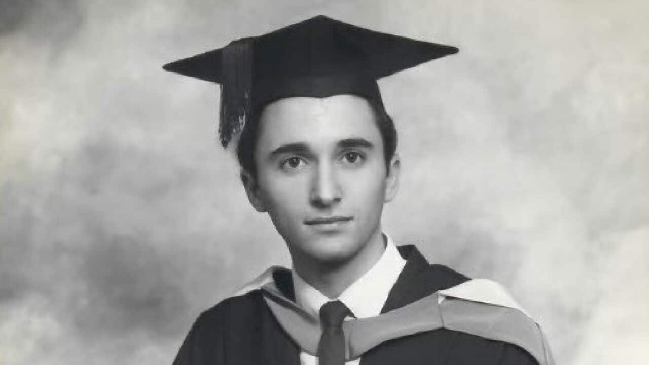Joe Pellegrino in a graduate robe with a diploma in his hands.