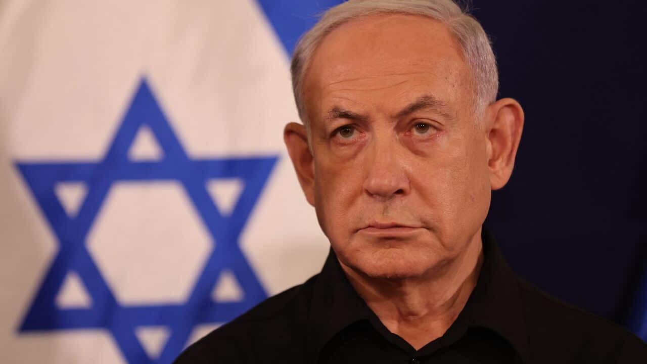 Benjamin Netanyahu sitting in front of an Israeli flag.