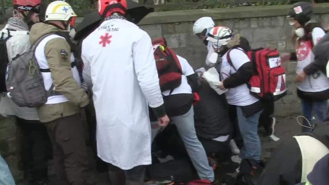 Emergency services attend to the protester who injured his hand
