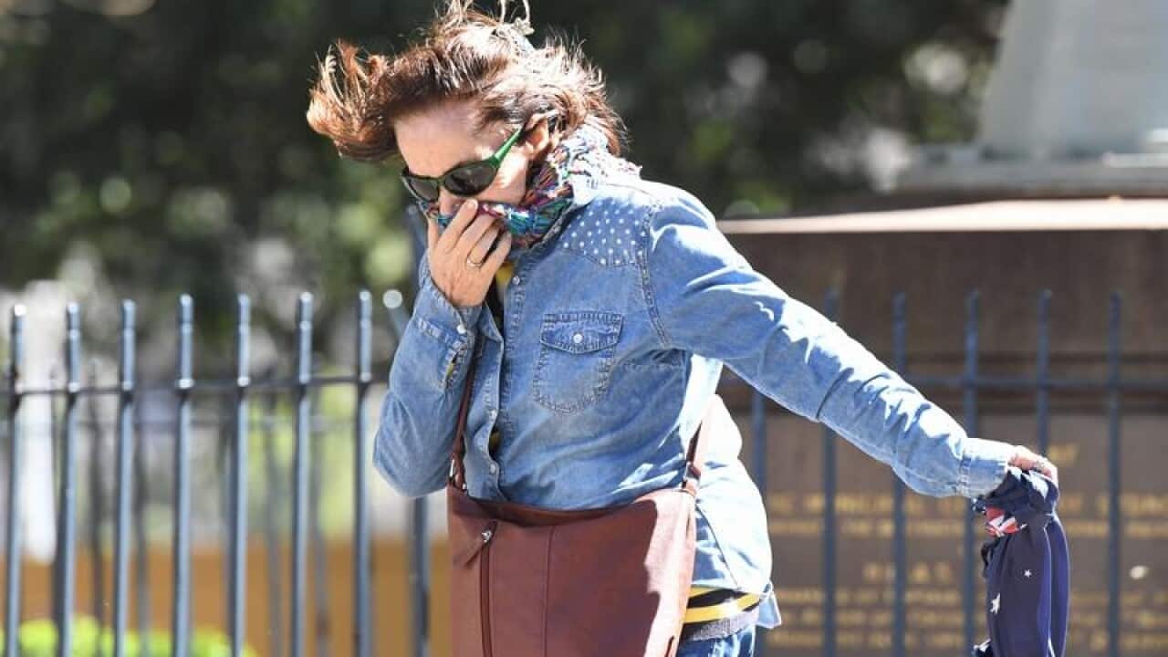 A woman reacts while walking through strong winds