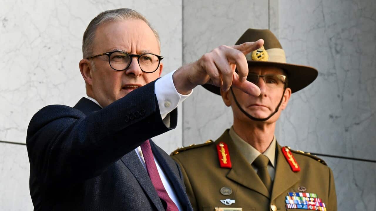 Australian Prime Minister Anthony Albanese points into the distance as he stands next to Australian Defence Force Chief Angus Campbell.