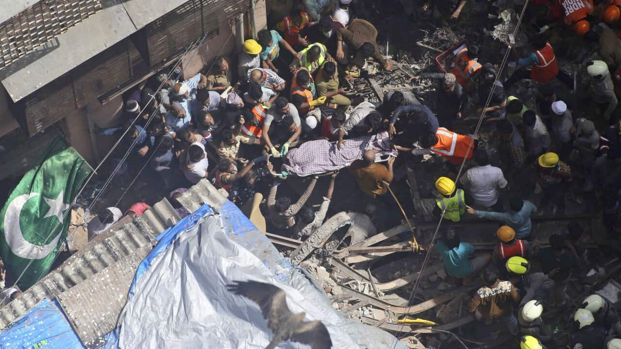 Rescuers work carry the body at the site of a building that collapsed in Mumbai, India.