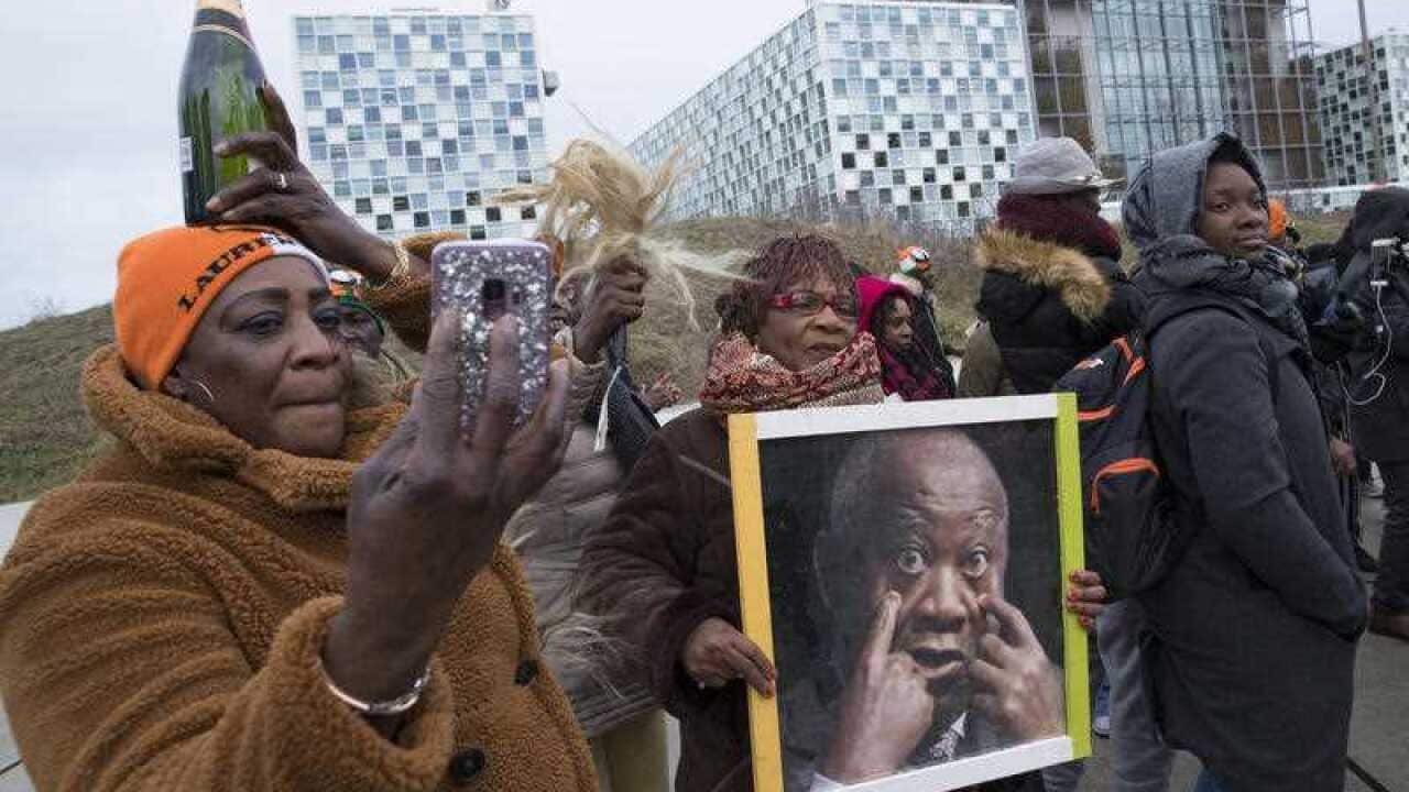 Supporters of Laurent Gbagbo celebrate outside the International Criminal Court with champagne ahead of his acquittal.