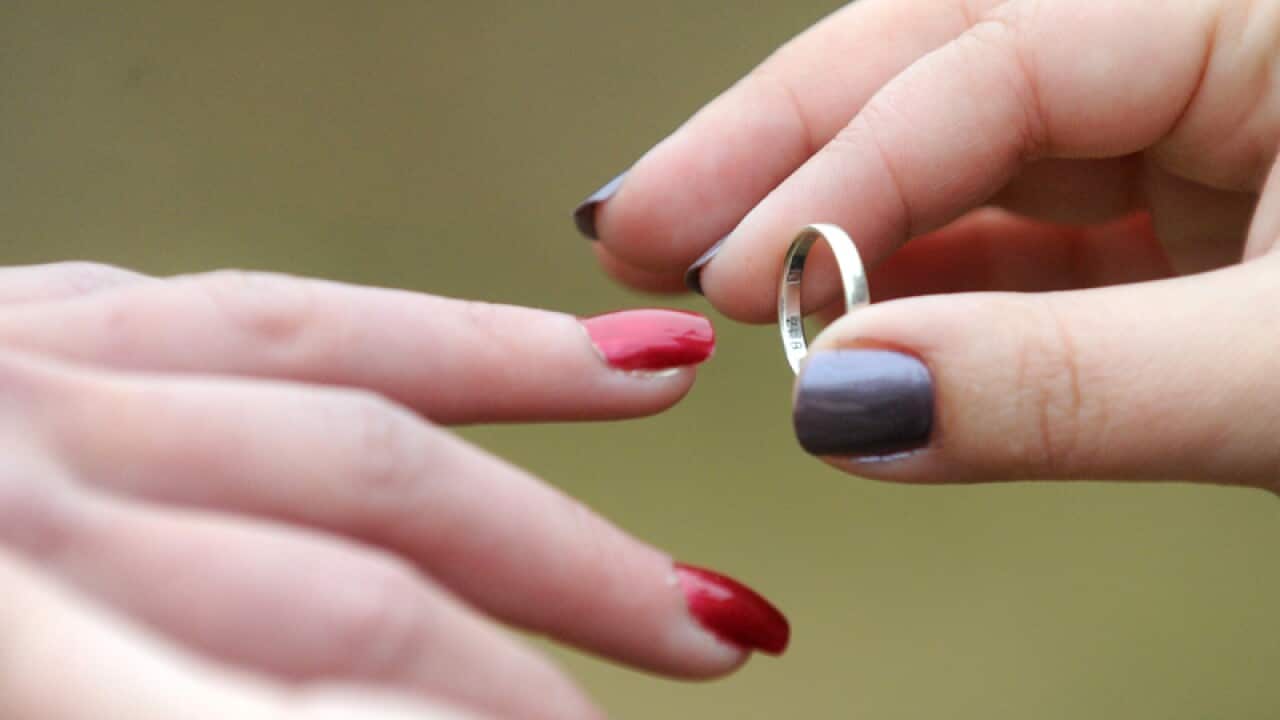 A woman places a wedding ring on her partners finger