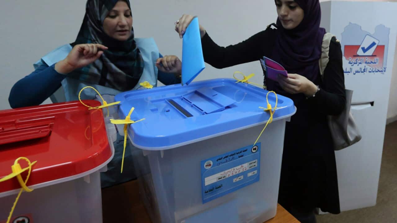 A Libyan woman casts her ballot at a polling station