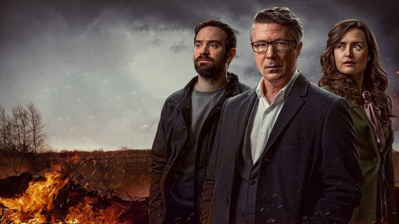 Three people stand against a blazing backdrop. They look defiant.