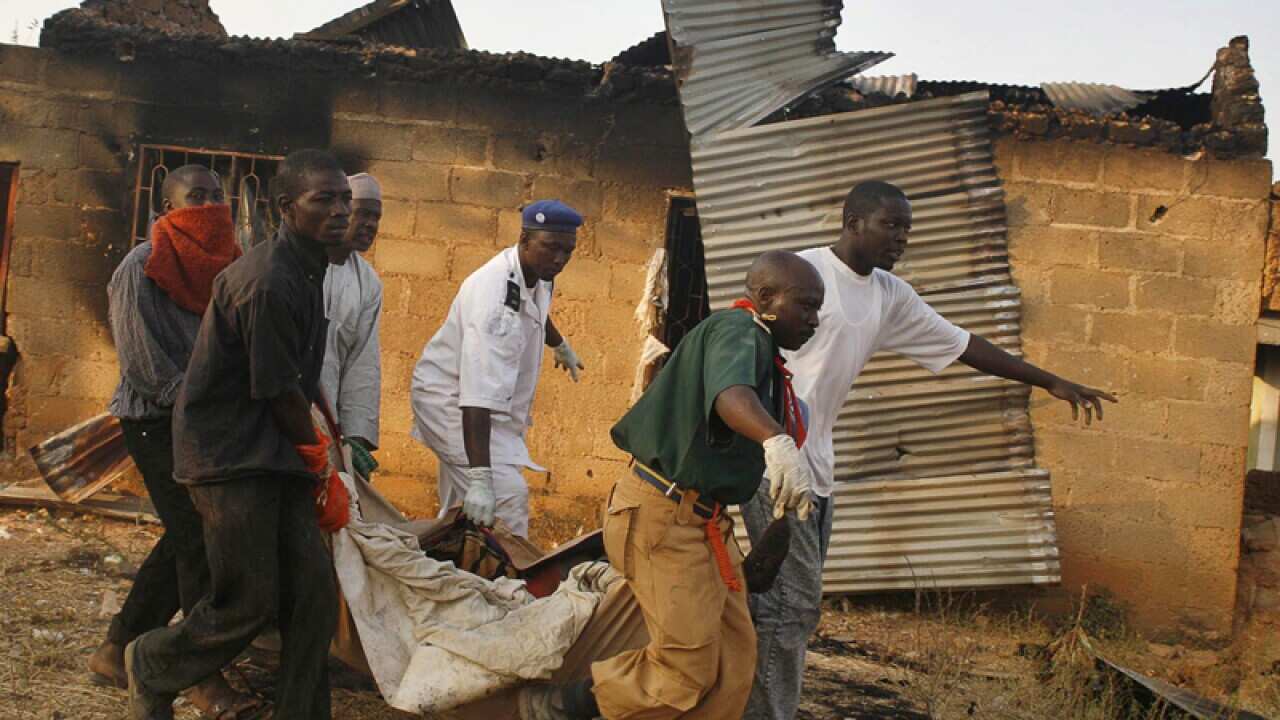Nigerian men carry a corpse