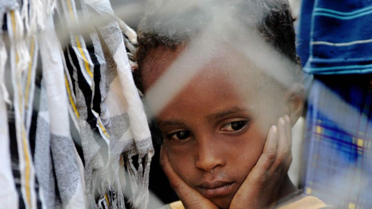 Four-year-old Bashir Hassan hangs his head in his hands as he and his family wait to be allowed to board a bus that transports newly arrived Somali refugees to a facility where they are officially registered as refugees. (Getty)
