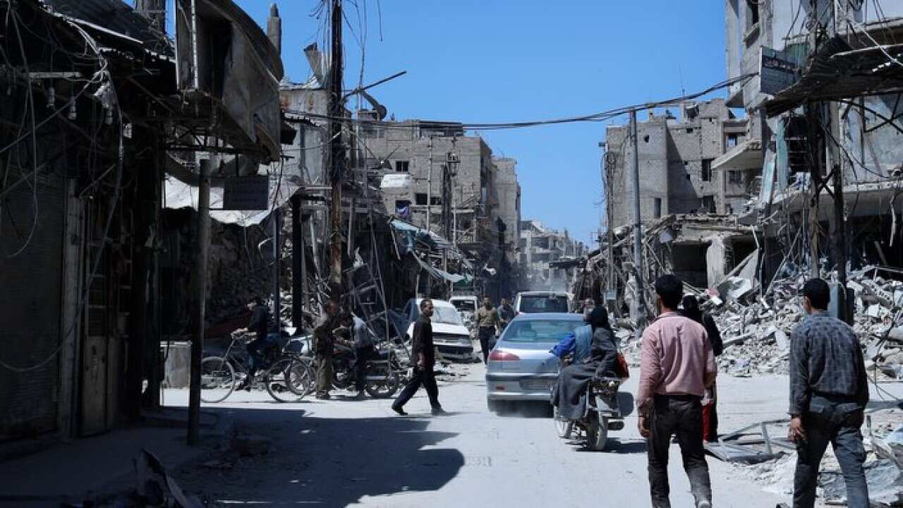 People walk in the town of Douma, the site of a suspected chemical weapons attack, near Damascus, Syria, Monday, April 16, 2018.