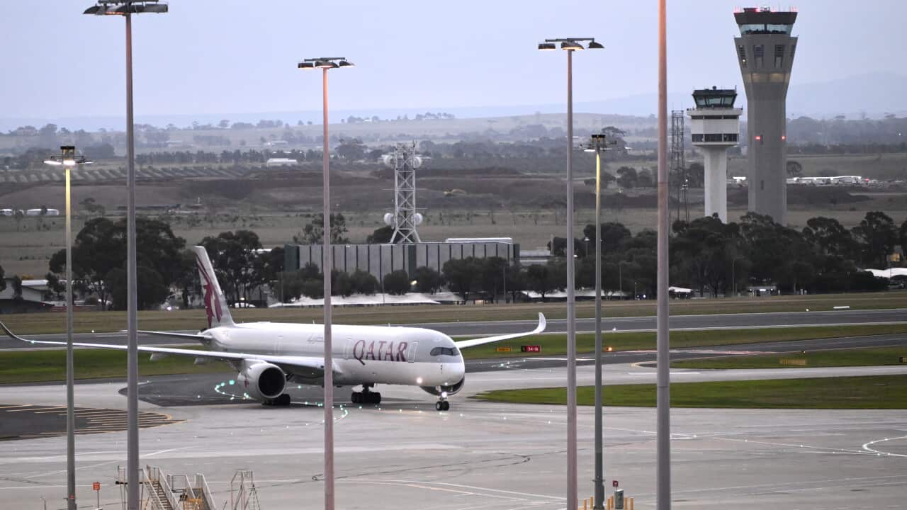 A plane that says QATAR on the side, on a tarmac