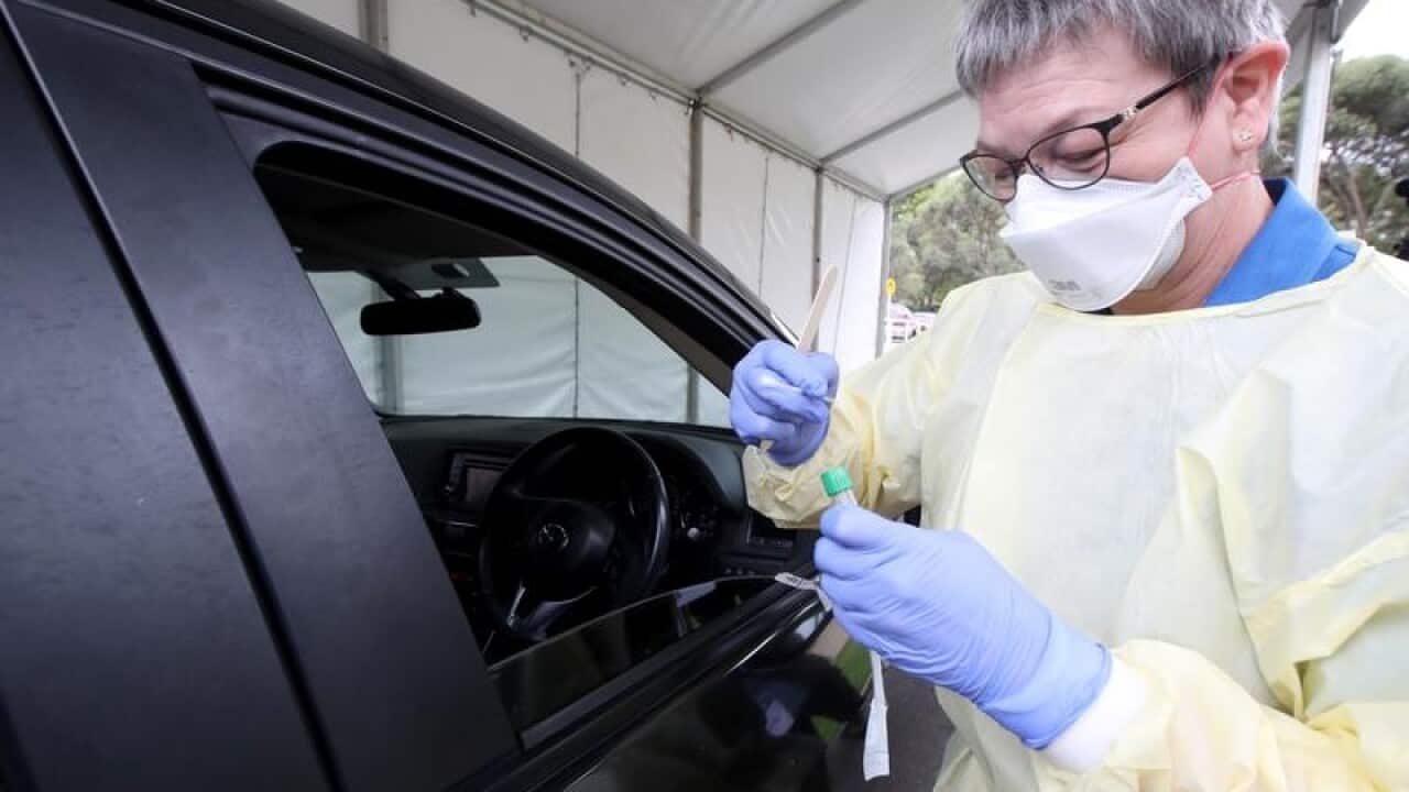 A nurse takes a sample from a driver at a COVID-19 testing facility.