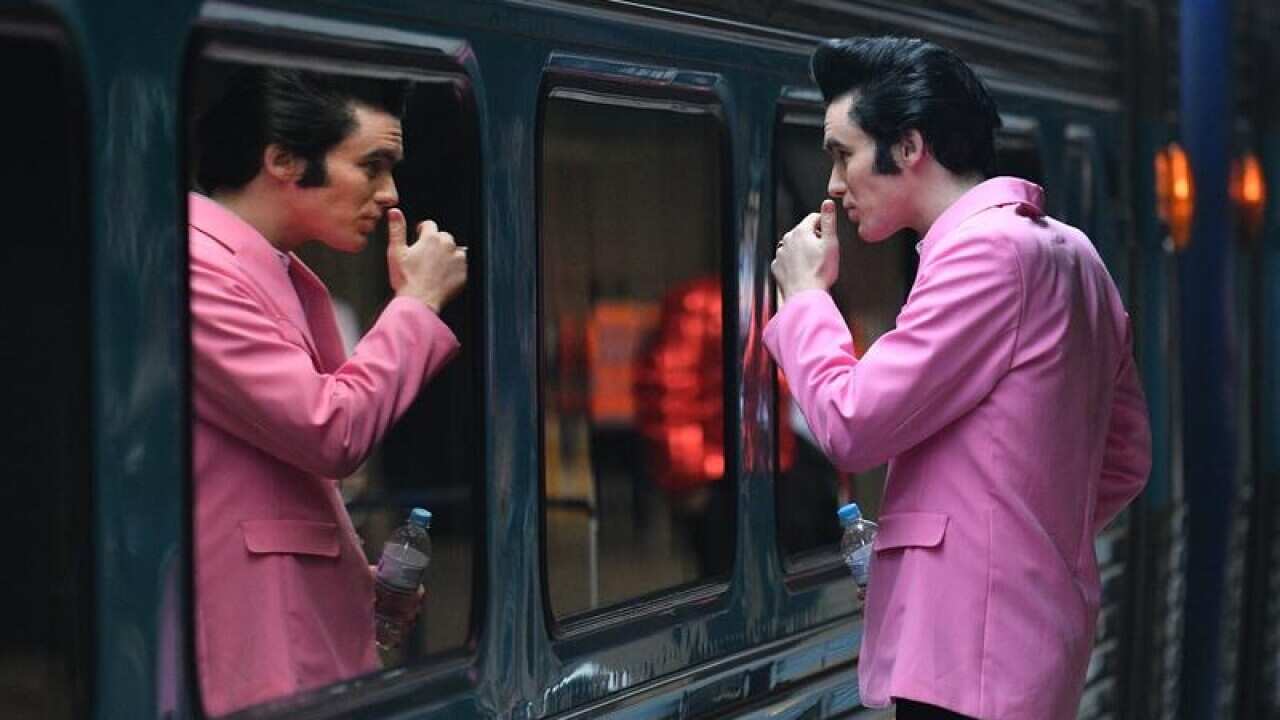 Elvis impersonator Brody Finlay looks at his reflection in a train