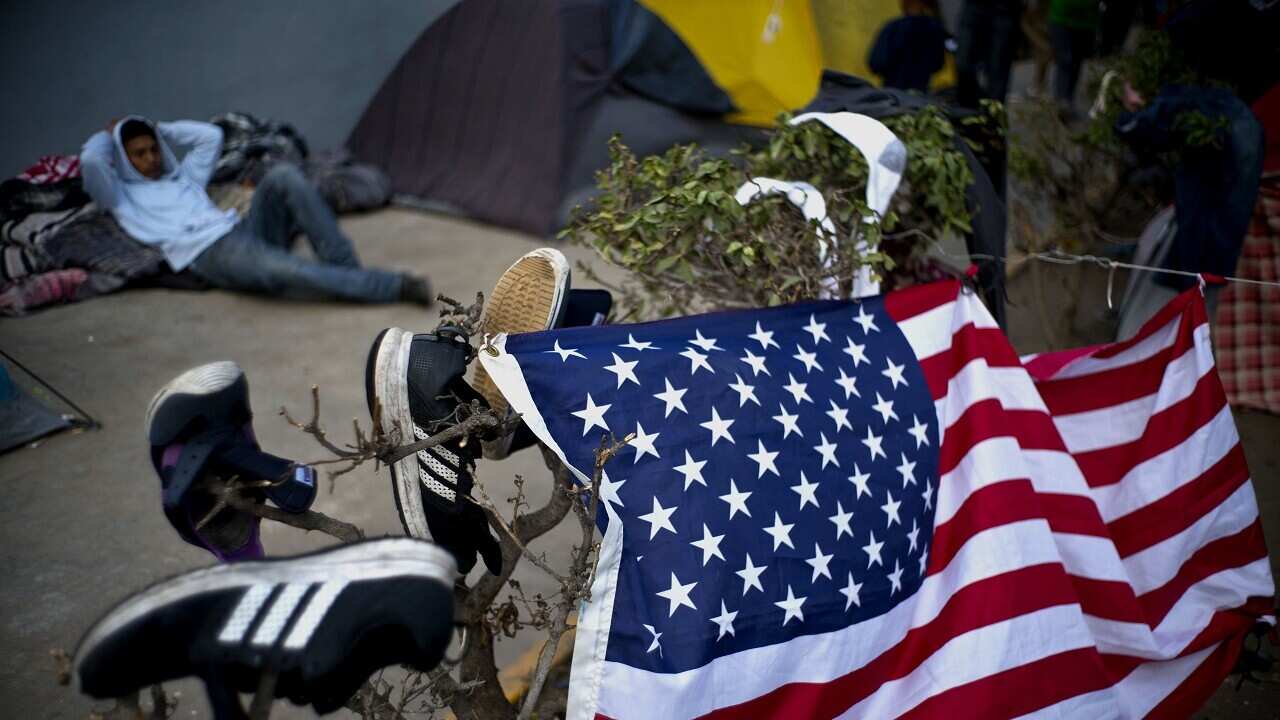 A migrant rests next to U.S flag at a sports complex where more than 5,000 Central American migrants are sheltering in Tijuana, Mexico.