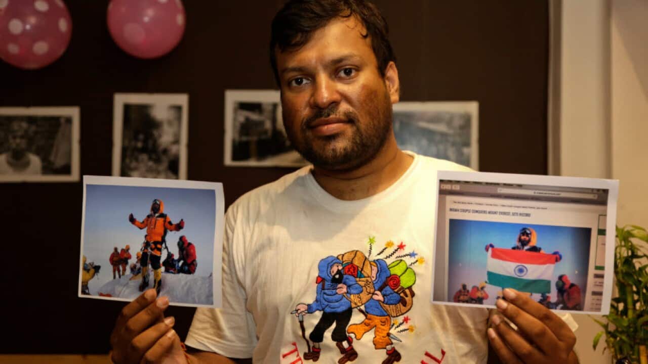 Indian climber Satyarup Sidhantha holds in his right hand a photo that shows him on Mt Everest, along with what he says is an altered version of the same image.