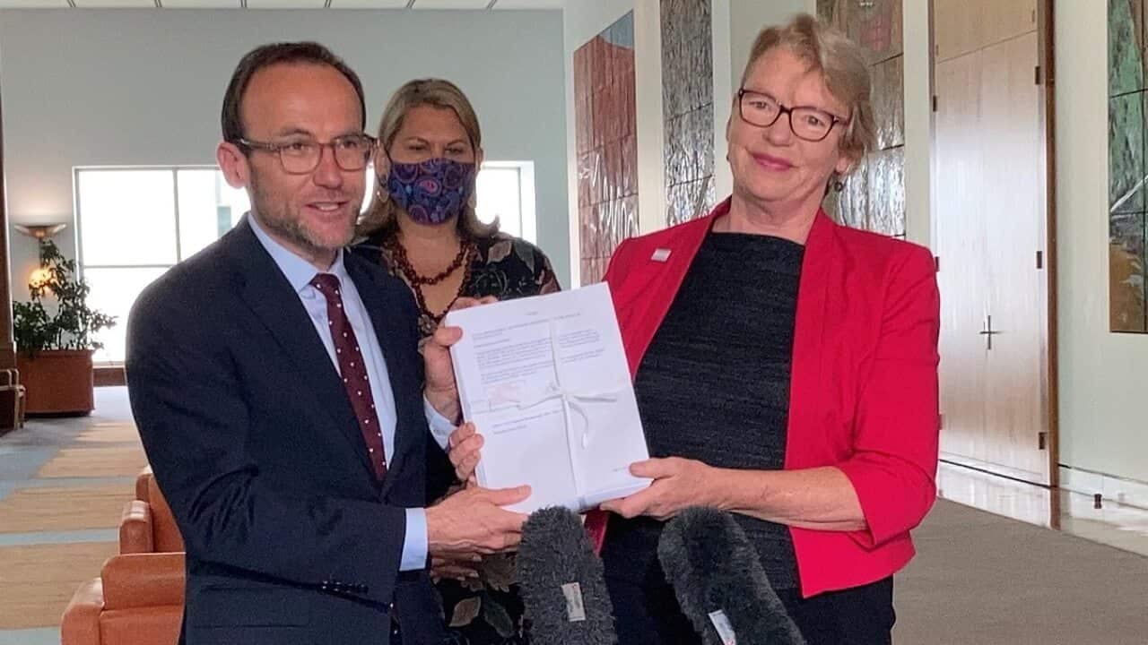 Greens leader Adam Bandt and senator Janet Rice hold up petition of over 150,000 signatories supporting gender-affirming healthcare free under Medicare.