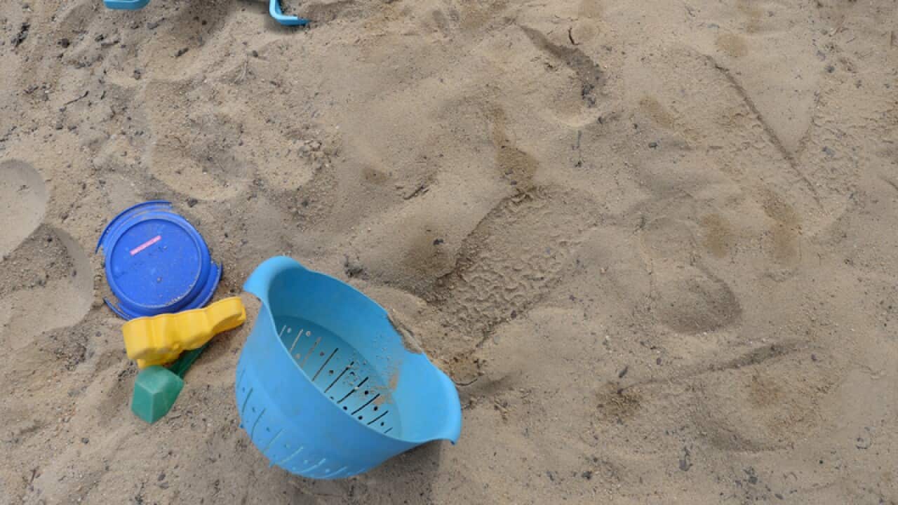 Toys are seen in a sandpit at a preschool