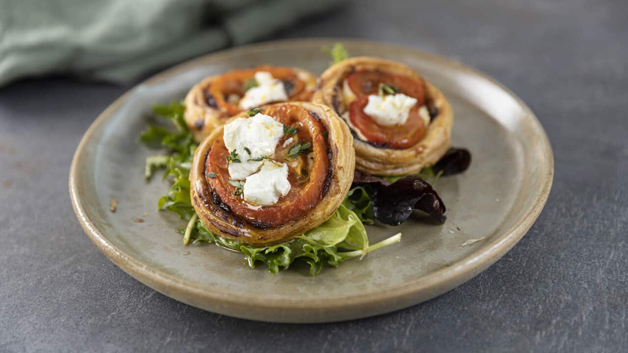 Three small, round olive and tomato tartlets with salad leaves.