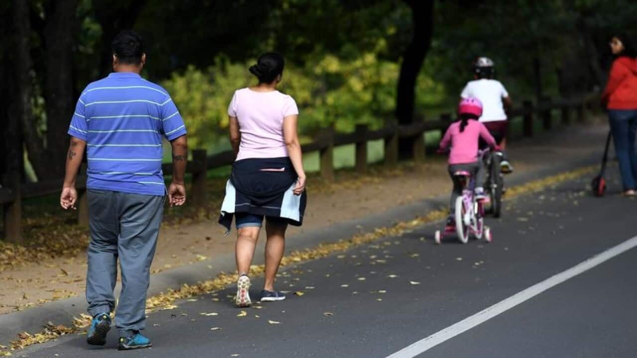 A young family walk and cycle in a park