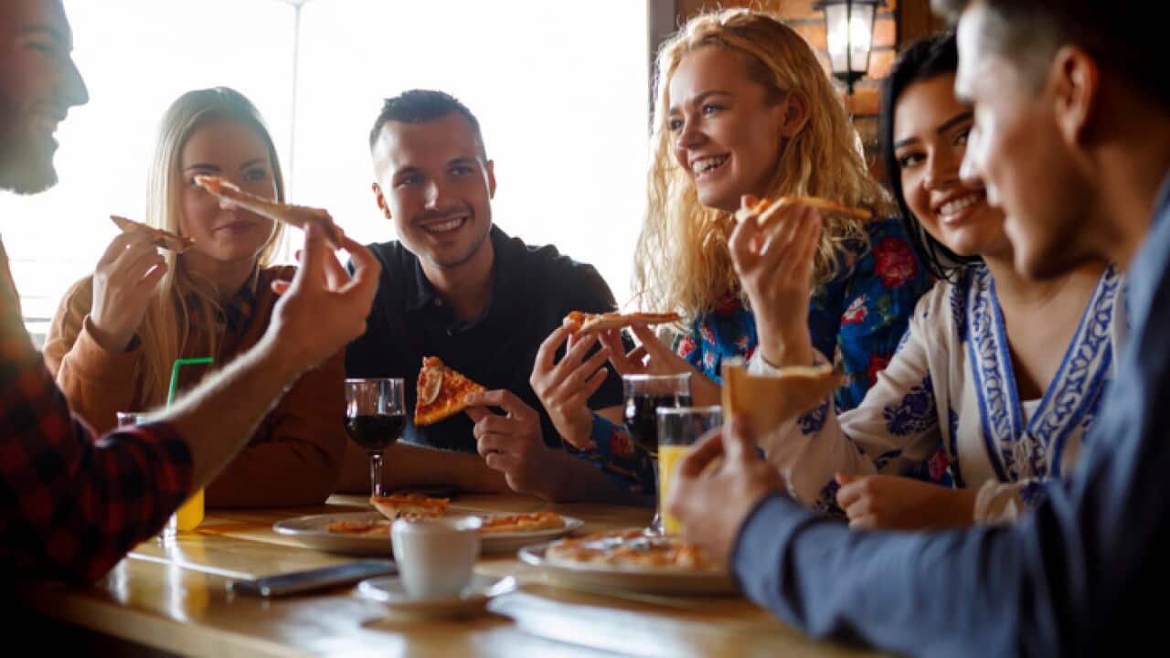 Group of friends eating pizza at restaurant