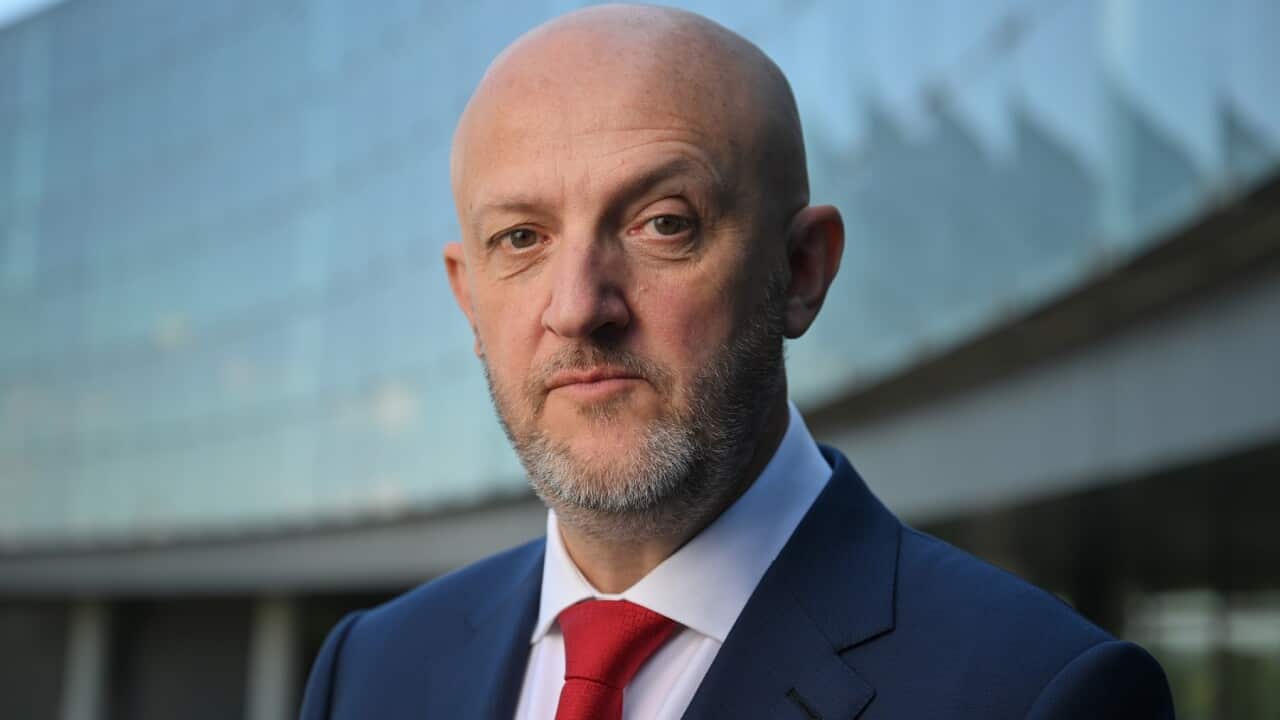 Portrait photo of a man wearing a blue suit and red tie
