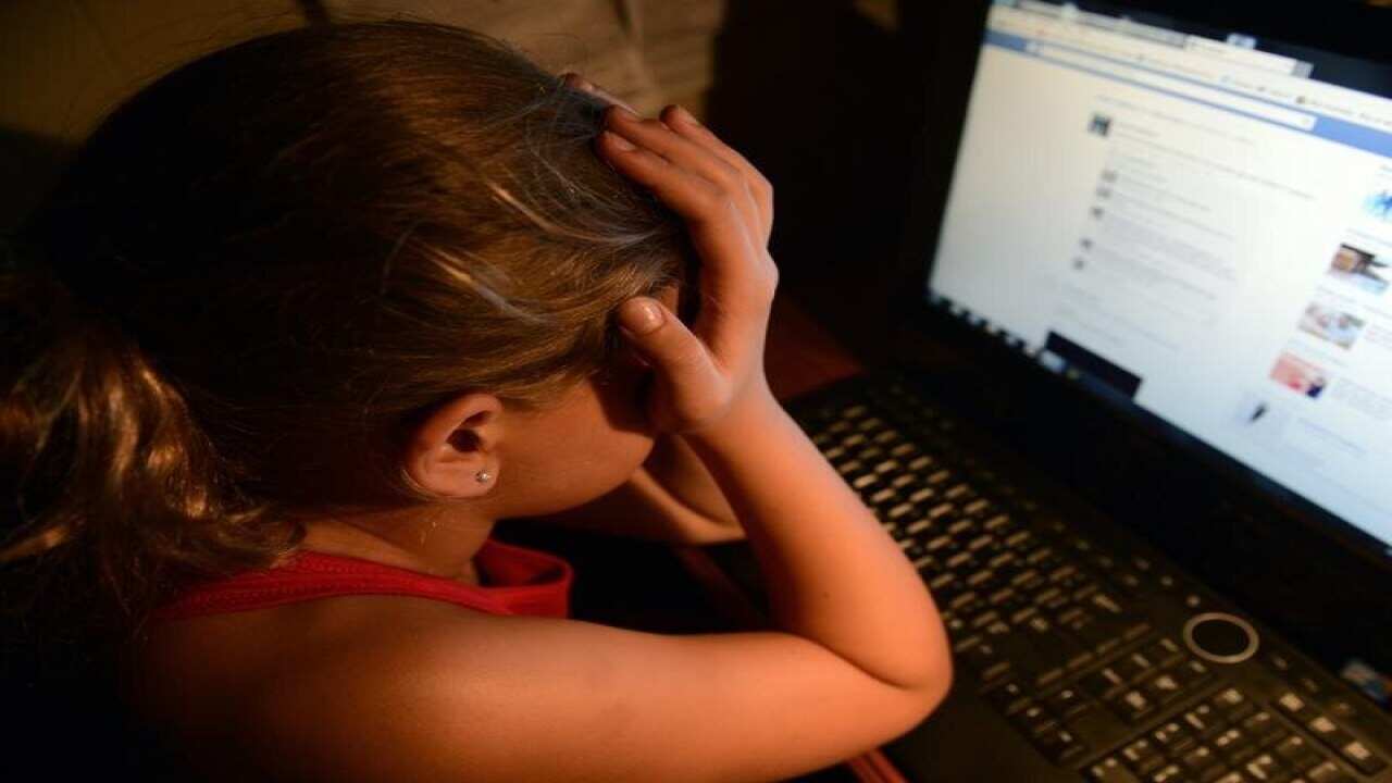 an upset young girl in front of a personal computer