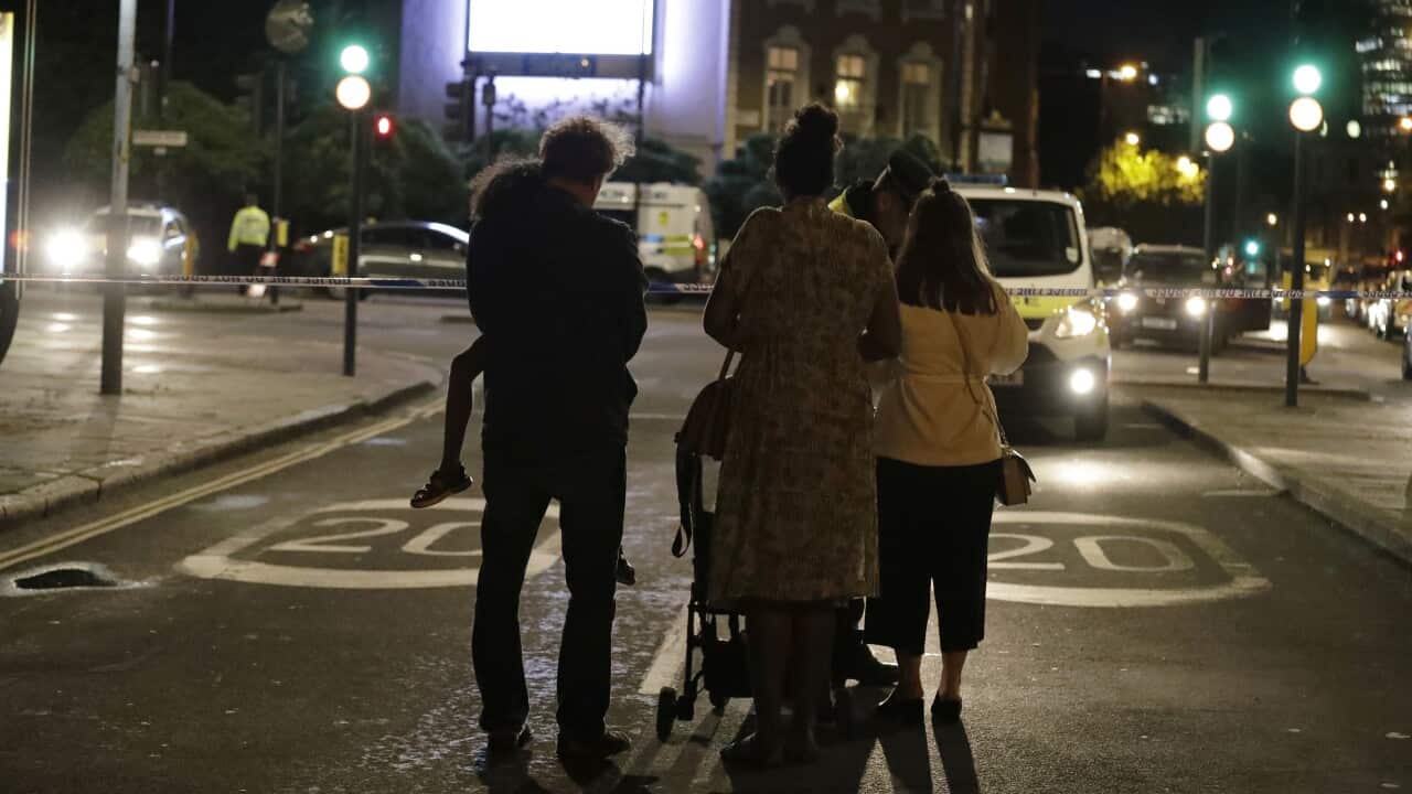 People wait by a cordon before being escorted through by police after the London attack.