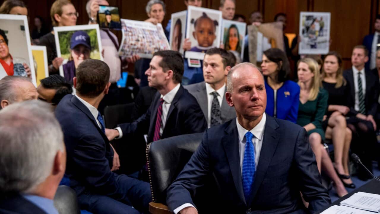 Boeing CEO Dennis Muilenburg watches as family members hold up photographs of those killed in 737 Max crashes