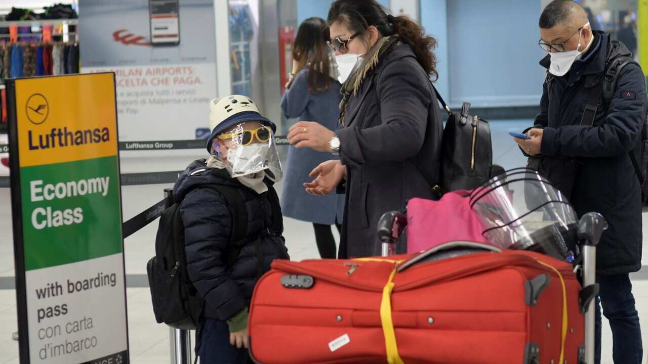 Passengers wear protective face masks inside the nearly-deserted Linate airport, in Milan, northern Italy, 9 March 2020.