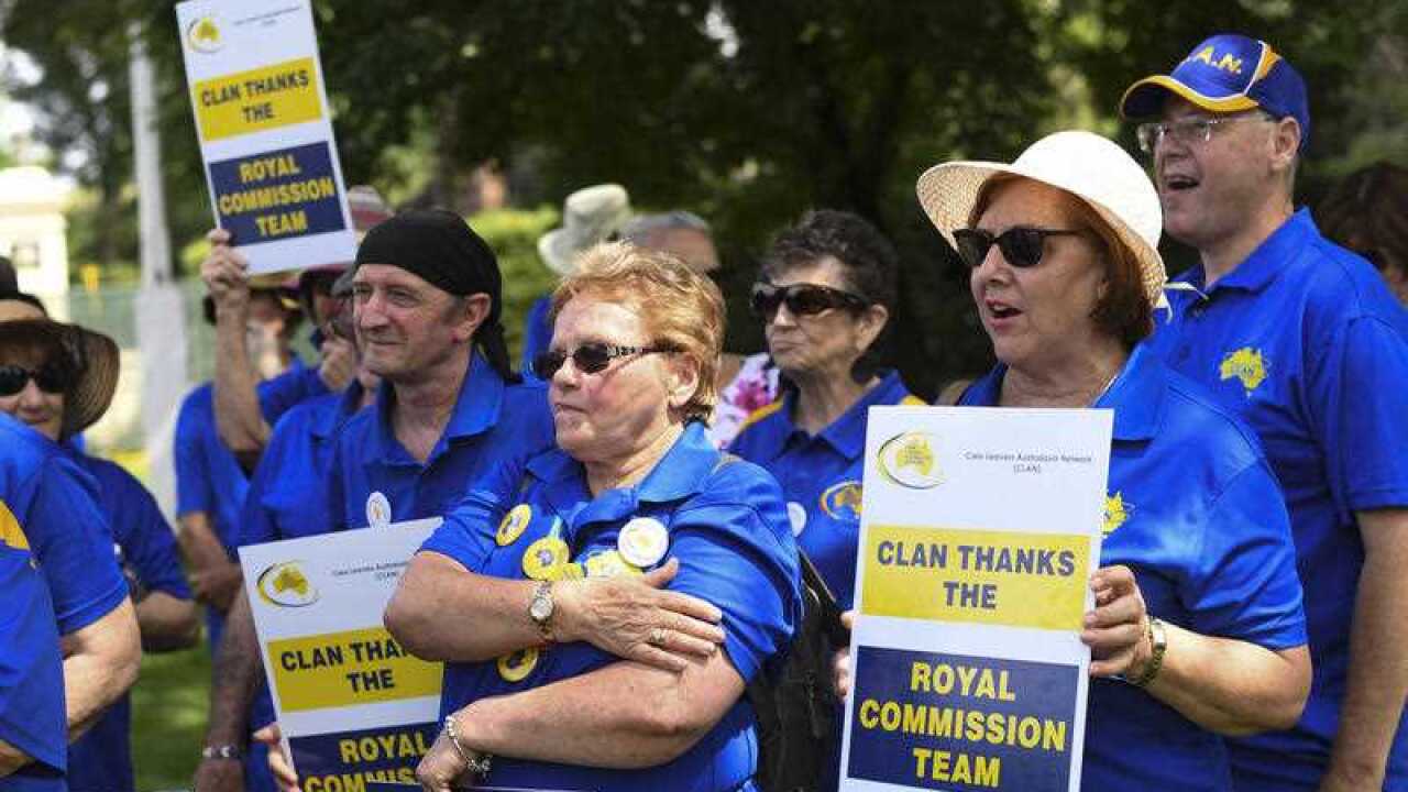 Members of the Care Leavers Australasia Network (CLAN) hold up signs thanking the Commission as they await the final report from the Royal Commission into Institutional Responses to Child Sexual Abuse outside Government House in Canberra, Friday.